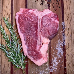 Foggy Bottoms Boys T-Bone Steak on wooden cutting board with salt, pepper corns and rosemary